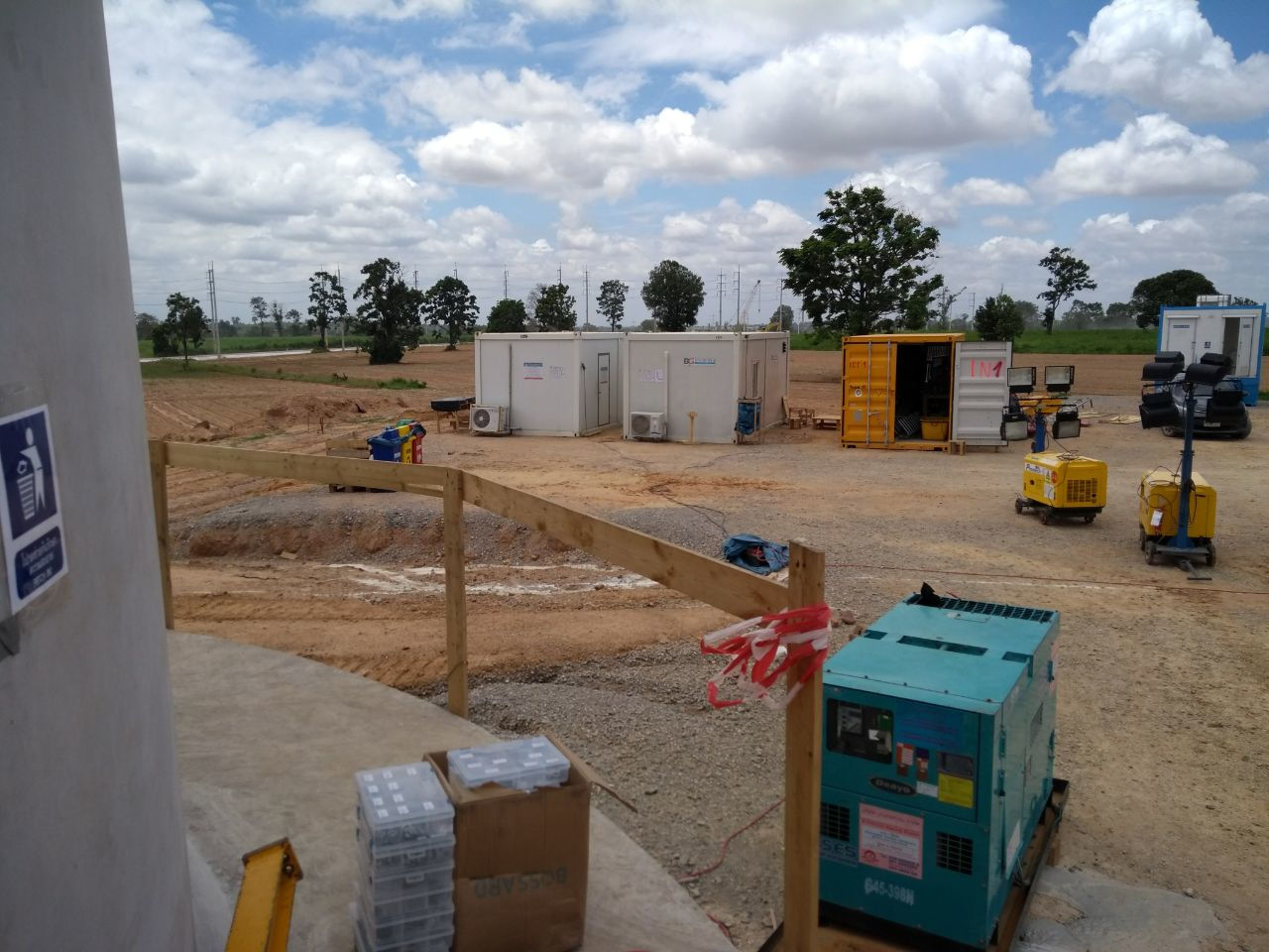 Auf dem Vorplatz eines Betonturmes stehen mehrere Baucontainer und Baumaschinen.